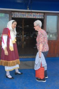 Cruise staff in traditional Greek costume welcoming passengers aboard on Athens 1 day to 3 islands cruise ship