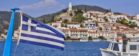 Greek flag with Poros Island harbor during one day cruise from Athens, Greece